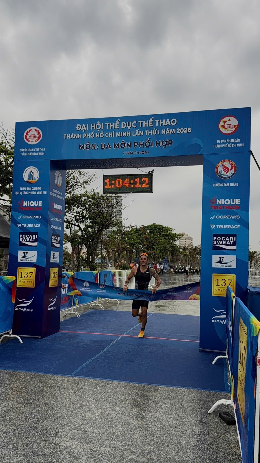 Lâm Quang Nhật breaking the tape for the overall win at the 2026 Ho Chi Minh City Triathlon Championship, Vũng Tàu — finish clock 1:04:12