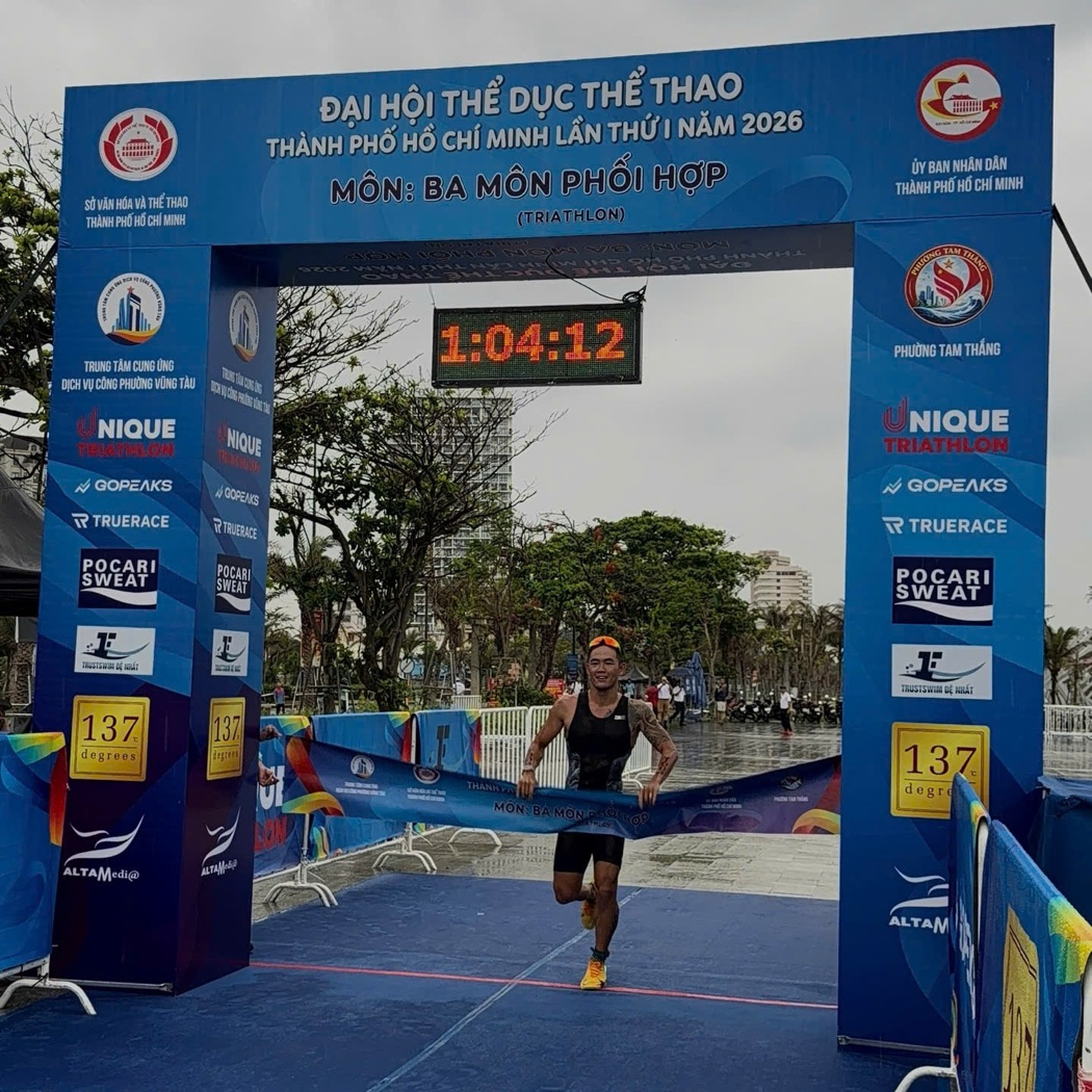 Lâm Quang Nhật breaking the tape for the overall win at the 2026 Ho Chi Minh City Triathlon Championship — finish clock 1:04:12, Vũng Tàu